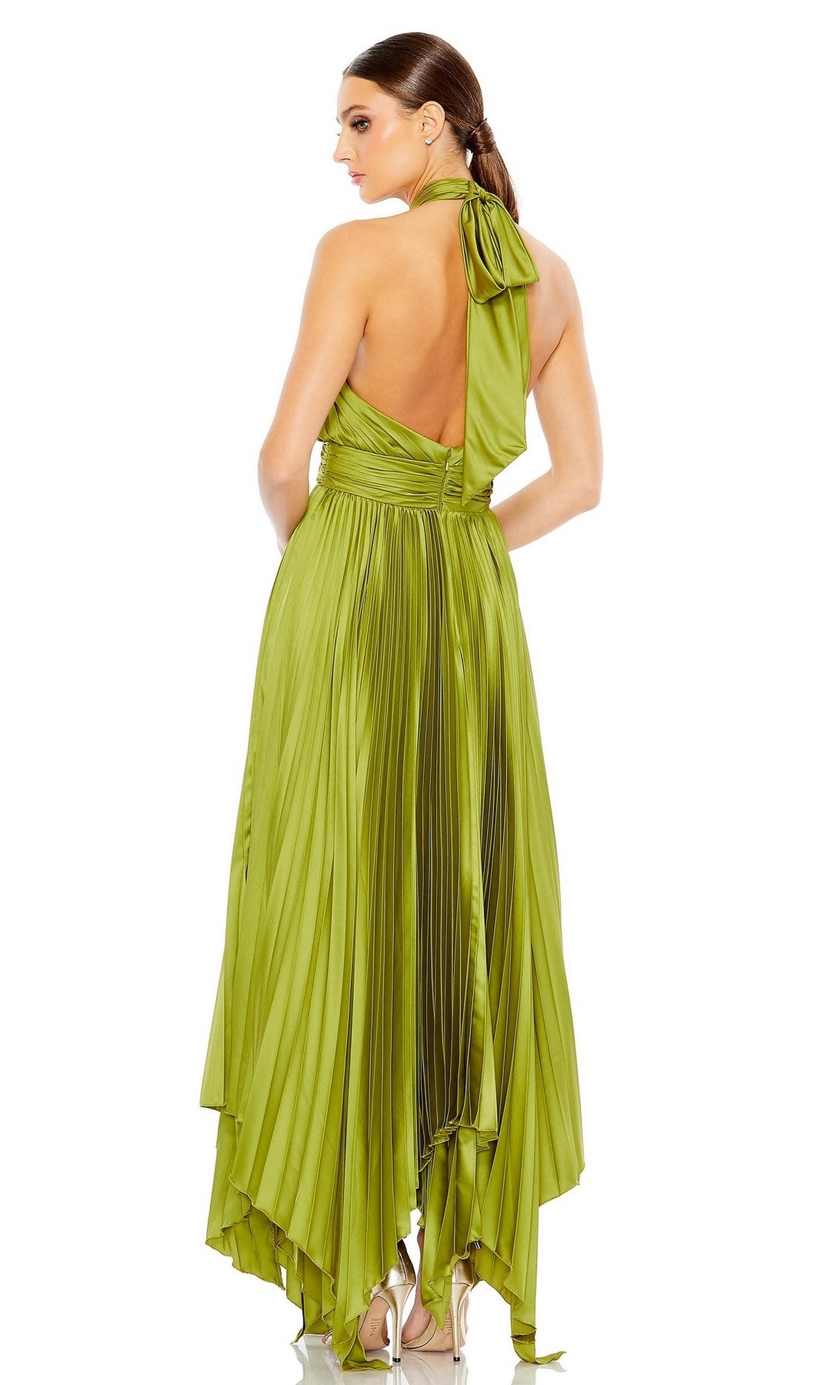 A woman stands with her back to the camera, wearing the Long Formal Dress 11302 by Mac Duggal—a shiny green pleated halter gown featuring an asymmetrical hemline.